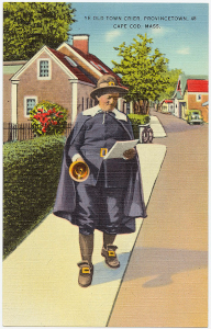 Town Crier dressed in traditional garb, walking down the sidewalk of a small town