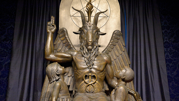 Bronze statue of baphomet with a boy and girl child looking up at him.