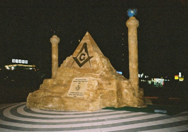 Night time picture of a stone monument at Eilat, Israel with a Freemason pyramid and two pillars.