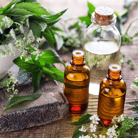 A jar of oil sitting on a table with herbs around it.